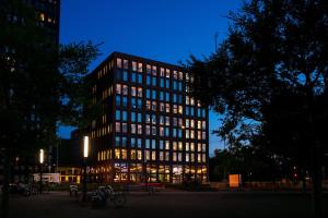 a tall building with many windows at night at Aloft Strasbourg City Centre in Strasbourg +50 photos