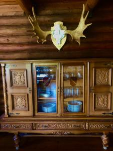 Kätkä Lake Lodge في Tervola: خزانة خشبية مع أبواب زجاجية مع أطباق في الداخل