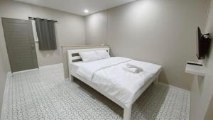 a small bedroom with a bed with white sheets at Juni House Chumphon in Chumphon