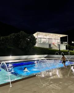 dos personas jugando en una piscina por la noche en FINCA LAS MARÍAS 2, en Vergara