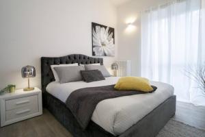 a bedroom with a large bed with a yellow pillow on it at 2 Bed Apartment Sleeps 4 - En-Suite Bath -Tv -WiFi in Asti