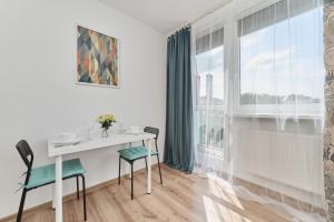 a white dining room with a table and chairs and a window at Studio with Sky Tower View Wrocław by Renters in Wrocław