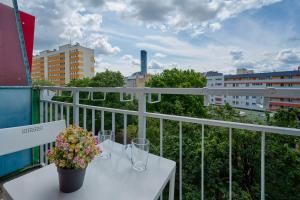 a white table with glasses and flowers on a balcony at Studio with Sky Tower View Wrocław by Renters in Wrocław