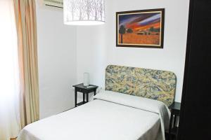 Habitación con 1 cama, 1 silla y 1 foto en Casa Rural La Fresneda, en Ubrique