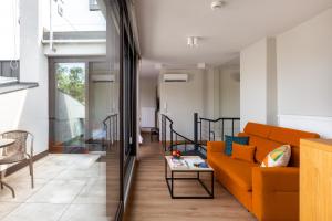 クラクフにあるArtSquare Fragola Apartmentsのリビングルーム(オレンジ色のソファ、テーブル付)