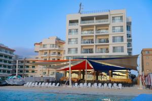 Triumph White Sands Hotel في مرسى مطروح: مبنى فيه خيمه وكراسي امام الماء