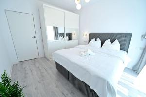 a white bedroom with a large bed with white sheets at FLH - The Lake Home - Apt 33 in Sibiu