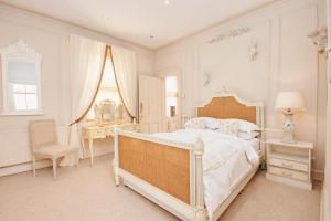 a white bedroom with a large bed and a chair at The Stray View - Harrogate in Harrogate