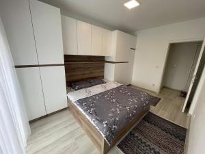 Dormitorio pequeño con cama y armarios blancos en Plis Apartment II, en Pristina