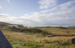 a view of a field with the ocean in the background at Joan's House in Tarskavaig