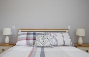 a bedroom with a white bed with two lamps at Joan's House in Tarskavaig