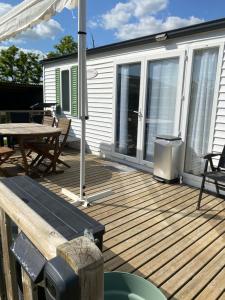 une terrasse en bois avec une table et une table de pique-nique dans l'établissement Mobil home camping privé, à Saint-Laurent-de-la-Prée