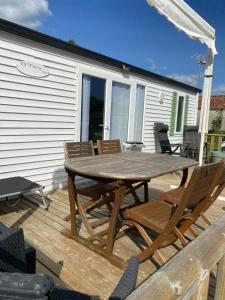 a wooden deck with a wooden table and chairs at Mobil home camping privé in Saint-Laurent-de-la-Prée