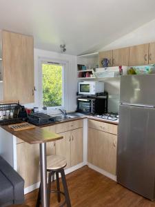 uma cozinha com armários de madeira e um frigorífico de aço inoxidável em Mobil home camping privé em Saint-Laurent-de-la-Prée