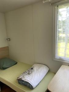 um pequeno quarto com uma cama e uma janela em Mobil home camping privé em Saint-Laurent-de-la-Prée