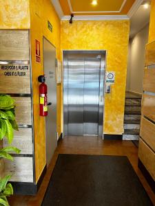 una hall con ascensore e estintore in un edificio di Pension Orois a Melide