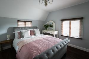 a bedroom with a bed with a pink blanket and windows at Accommodation at Salomons Estate in Royal Tunbridge Wells