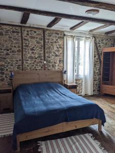 a bedroom with a bed and a stone wall at Le Petit Chat in Beaulieu-sur-Dordogne