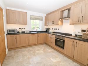 a kitchen with wooden cabinets and black counter tops at 3 Pensyflog Barns in Porthmadog