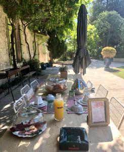 una mesa con platos de comida y una sombrilla en Le Mas Neuf 1752 en Arlés