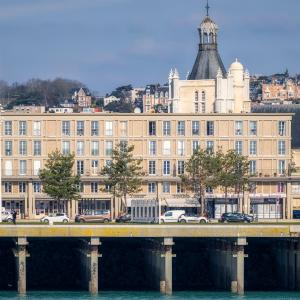 un grand bâtiment avec un pont sur une étendue d'eau dans l'établissement Résidence GABRIELLE, au Havre