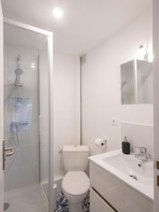 a white bathroom with a toilet and a sink at Résidence GABRIELLE in Le Havre