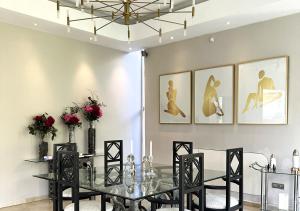Villa Majestueuse 5 étoiles à Casablanca في الدار البيضاء: غرفة طعام مع طاولة زجاجية وكراسي سوداء