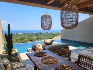 a patio with a table and chairs and a view of the ocean at Memorias Villas and Suites in Vasilikos
