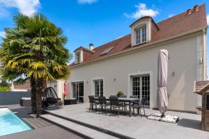 a patio with a table and chairs and a palm tree at *Villa-Disneyland-Paris* 10pers, Fitness, Cinema in Gouvernes