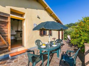einem blauen Tisch mit Stühlen und einem Sonnenschirm auf einer Terrasse in der Unterkunft Holiday Home Grilli by Interhome in Scansano
