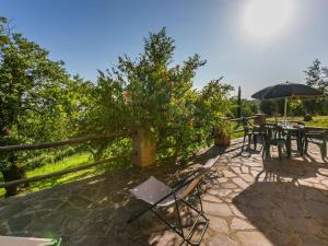 eine Terrasse mit Tischen, Stühlen und einem Sonnenschirm in der Unterkunft Holiday Home Grilli by Interhome in Scansano
