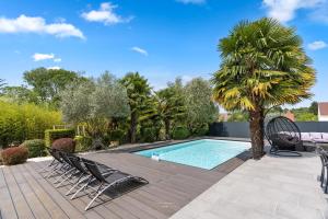 a swimming pool with chairs and a palm tree at *Villa-Disneyland-Paris* 10pers, Fitness, Cinema in Gouvernes