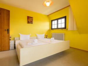 ein Schlafzimmer mit einem großen Bett mit gelben Wänden in der Unterkunft Apartment Wichtelmännchen by Interhome in Dittishausen