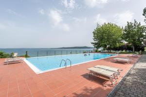 een zwembad met tafels en banken naast het water bij Casa Vacanze Blue Lake in Padenghe sul Garda