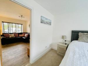 a bedroom with a bed and a living room with a couch at Little Greenway Holiday Bungalow in Galmpton-on-the-Dart