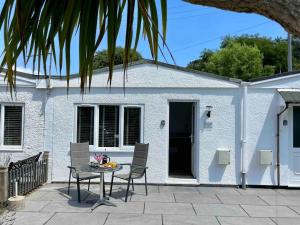 a patio with a table and chairs in front of a white building at Little Greenway Holiday Bungalow in Galmpton-on-the-Dart