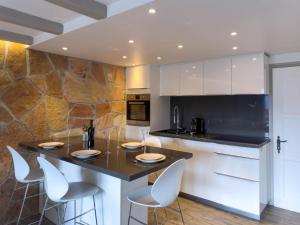 a kitchen with a island with white cabinets and white chairs at Apartment Stem 2 by Interhome in Verbier