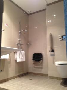ein Bad mit einer Dusche, einem WC und Handtüchern in der Unterkunft Crowne Plaza Verona Fiera, an IHG Hotel in Verona