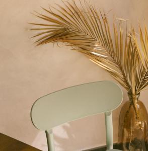 a white chair next to a vase with a plant at Sãone Guesthouse & Coworking in Ericeira