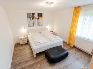 a bedroom with a white bed and a black ottoman at Holiday Home Quelle by Interhome in Dittishausen