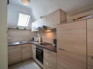 una pequeña cocina con armarios de madera y fregadero en Holiday Home Am Sternberg 38 by Interhome, en Frankenau