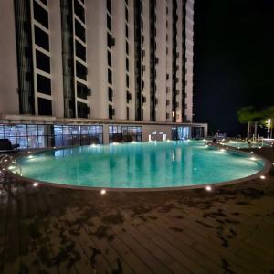 a large swimming pool at night with tall buildings at Qilala DualView by The Shore in Kota Kinabalu