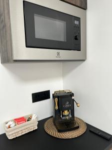 una macchinetta del caffè nera seduta su un bancone sotto un forno a microonde di Core e core a Napoli