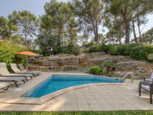 a swimming pool with chairs and an umbrella at Villa Le Puit des Oliviers I by Interhome in La Cadière-dʼAzur