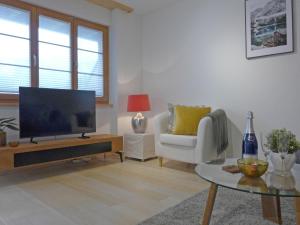 a living room with a television and a chair and a table at Apartment Panoramapark Soleil Haus D Apt 3 by Interhome in Wengen