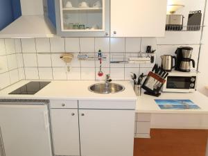 a kitchen with white cabinets and a sink at Apartment Tossens-6 by Interhome in Butjadingen OT Tossens +12 photos
