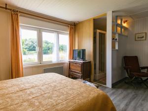 a bedroom with a bed and a tv and a window at Holiday Home La Littorine by Interhome in Kersiroux