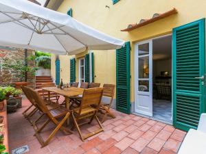 um pátio com uma mesa, cadeiras e um guarda-sol em Holiday Home San Lazzaro by Interhome em Montevettolini