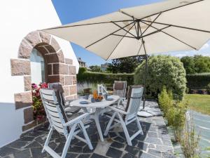 - une table et des chaises blanches sous un parasol sur la terrasse dans l'établissement Holiday Home Reve de Mer - LOQ215 by Interhome, à Locquirec