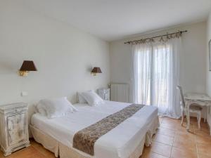 ein Schlafzimmer mit einem großen weißen Bett und einem Tisch in der Unterkunft Villa Le Puit des Oliviers 2 by Interhome in La Cadière-dʼAzur